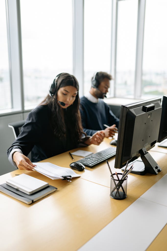 Call center agents handling customer inquiries at modern office desks, focused and professional.